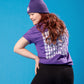 Mädchen steht mit dem Rücken zur Kamera. Sie trägt ein violettes T-Shirt mit kleinem 	Weltspiele Logo auf der Brust und einer violetten Mütze.
