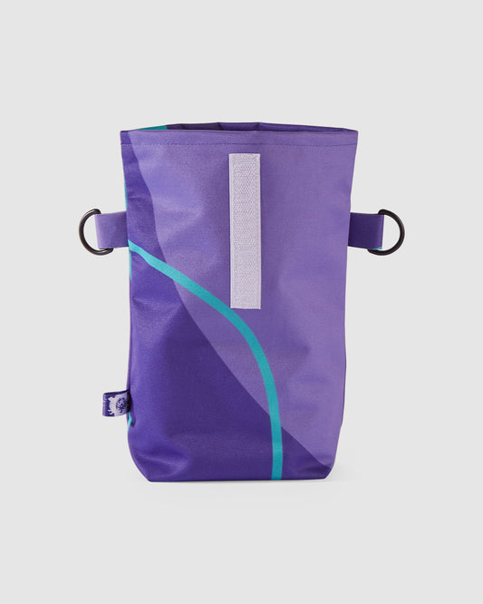 Aufgerollte kleine Rolltop Tasche mit violettem und türkisenem Muster.  