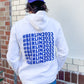 Mann steht vor einer Wand mit dem Rücken zur Kamera. Er trägt weißen Hoodie mit #Berlin2023 Schriftzug auf dem Rücken und violettes Cap mit Logo