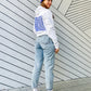 Frau trägt weißen Hoodie mit Weltspiele Logo und violette Mütze mit Logo 