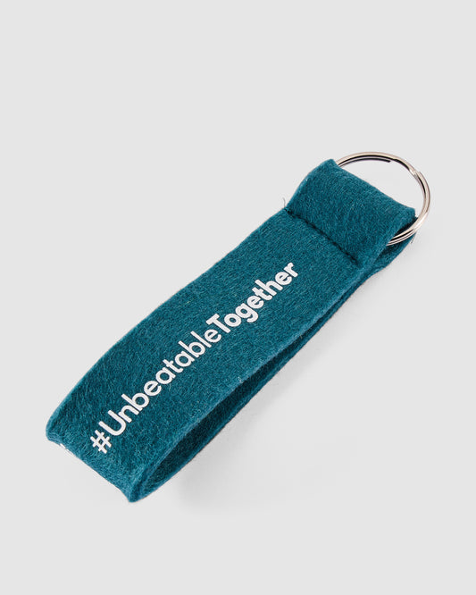 Schlüsselanhänger in petrol mit weißem #UnbeatableTogether Schriftzug hinten