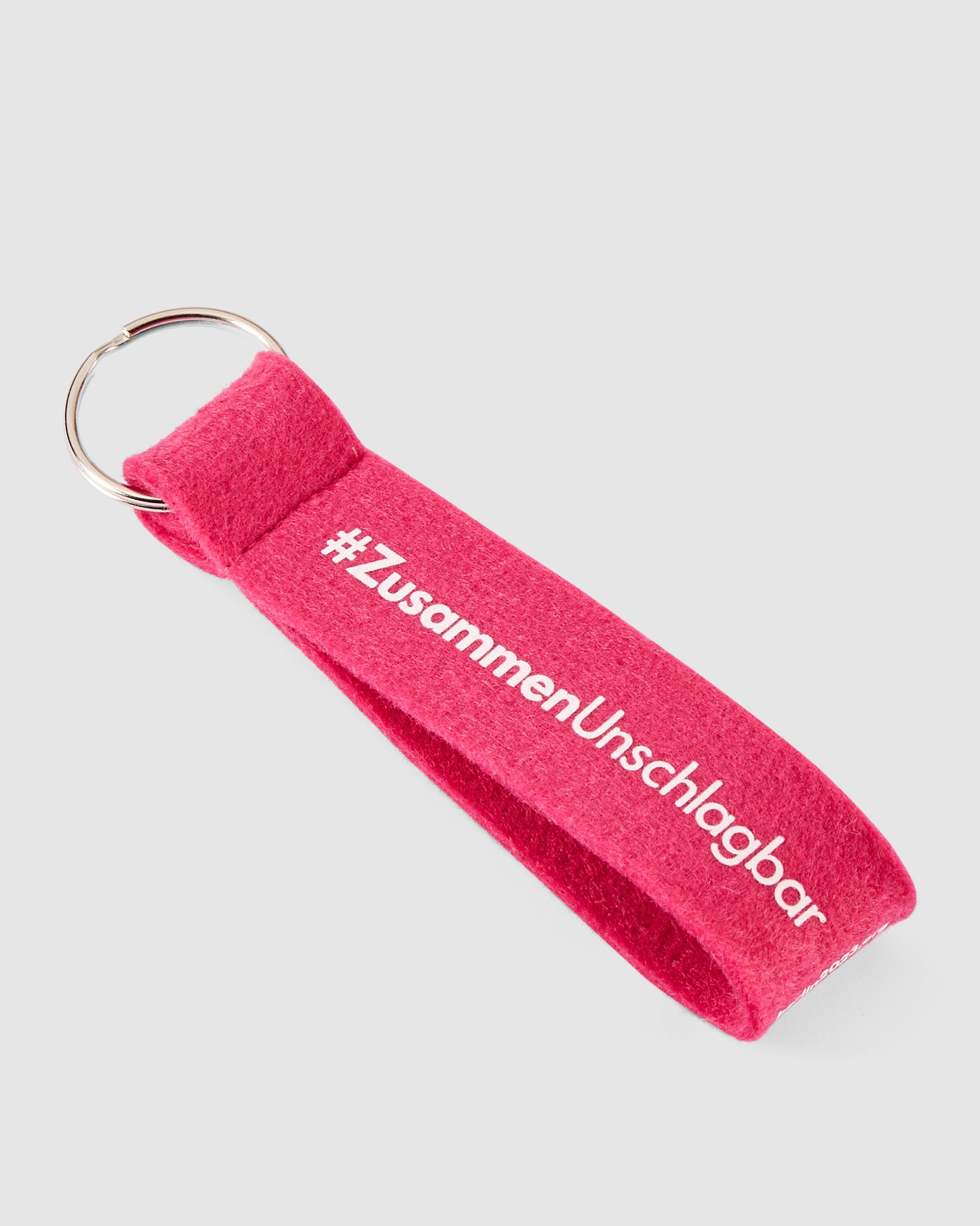 Schlüsselanhänger in pink mit #ZusammenUnschlagbar Schriftzug weiß vorne