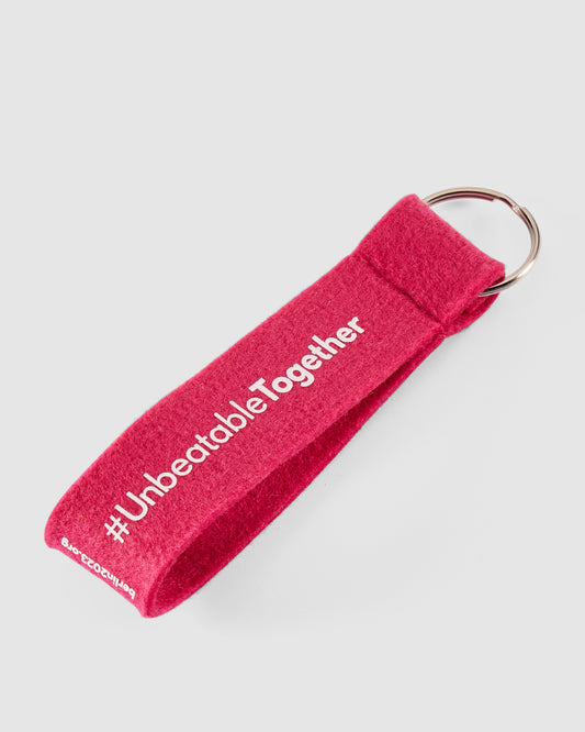 Schlüsselanhänger in pink mit weißem #UnbeatableTogether Schriftzug hinten