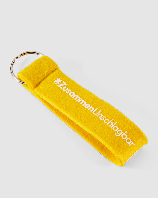 Schlüsselanhänger in gelb mit #ZusammenUnschlagbar Schriftzug weiß vorne
