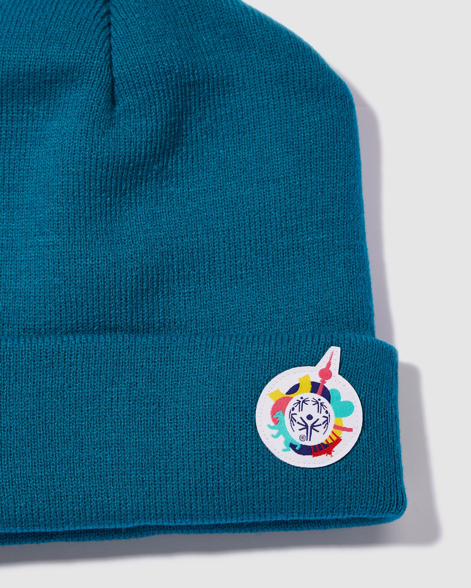 Nahaufnahme einer  Mütze in petrol mit kleinem Weltspiele Logo