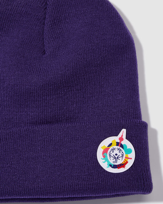 Nahaufnahme Mütze in violet mit kleinem Weltspiele Logo