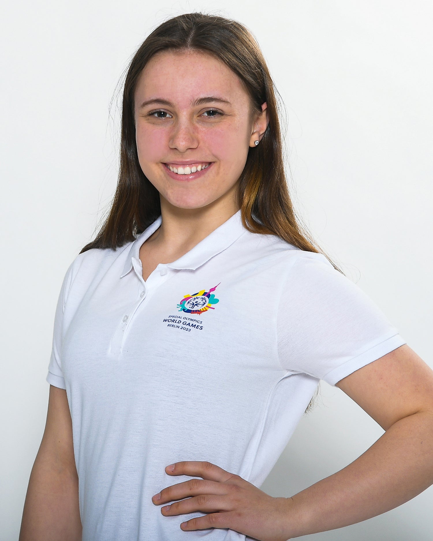 Mädchen trägt weißes Polo-Shirt mit kleinem Weltspiele Logo auf der Brust 