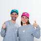 Mann und Mädchen stehen nebeneinander. Beide tragen graue Sweatshirts mit 	einem kleinen Weltspiele Logo auf der Brust.
