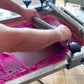 Mann bedruckt händisch ein weißes T-Shirt mit pinker Farbe.
