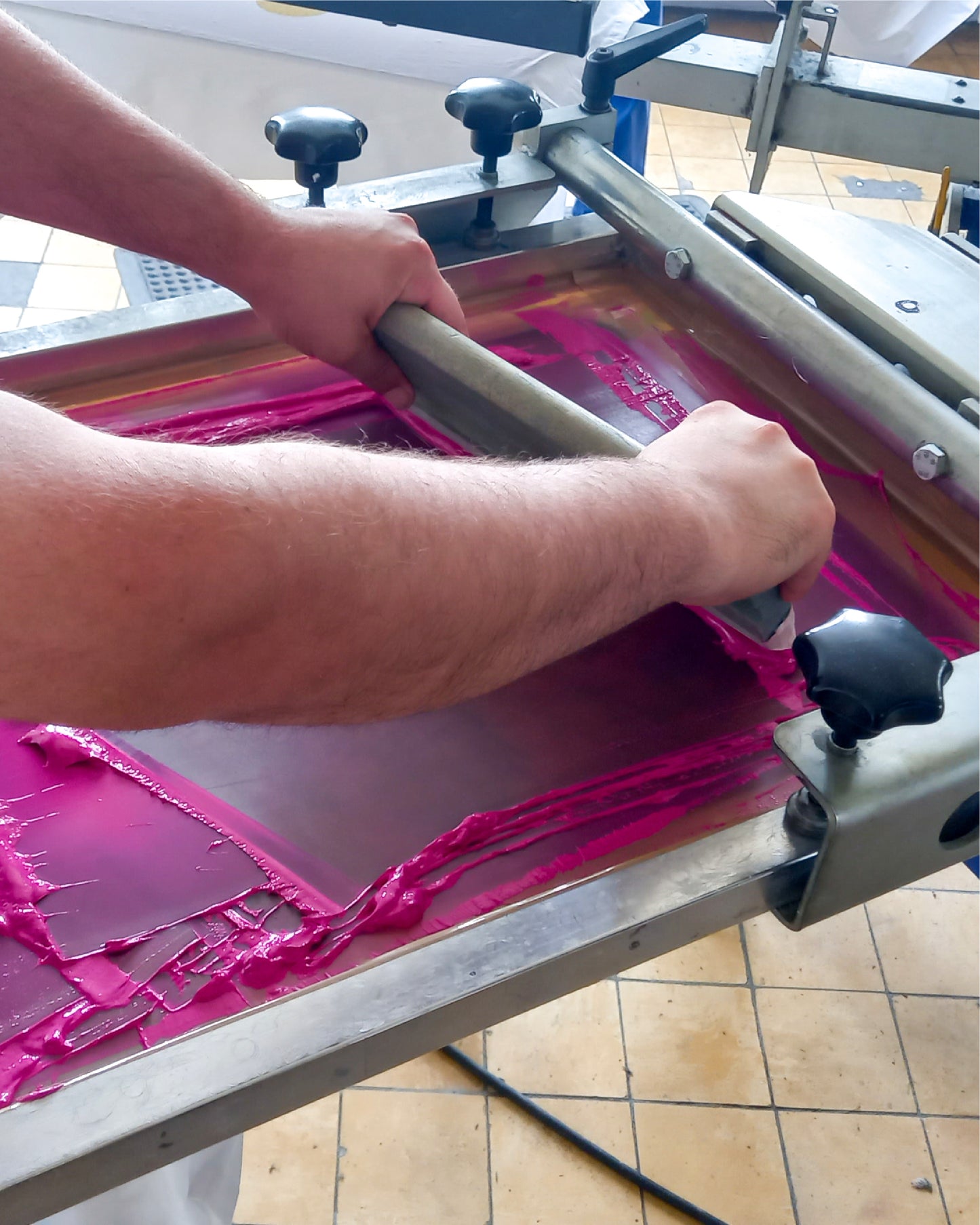Mann bedruckt händisch ein weißes T-Shirt mit pinker Farbe.