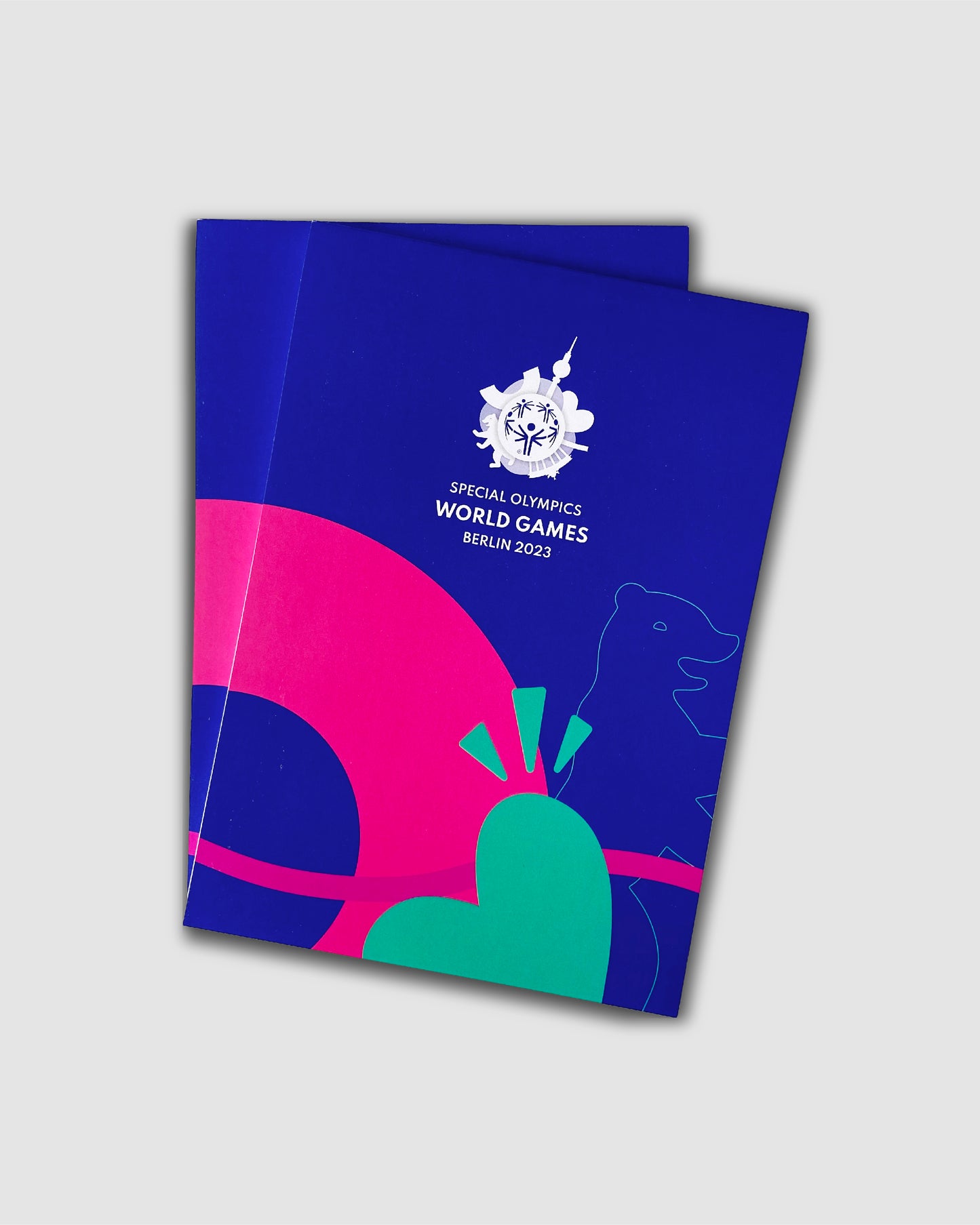 Deckblatt des blauen Notizblocks mit buntem Weltspiele Design und weißem Special Olympics World Games Berlin 2023 Logo. 